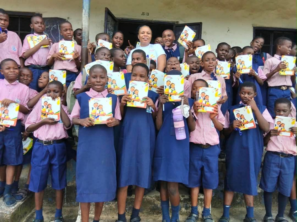 Junior secondary school students proudly displaying newly received exercise books and school supplies